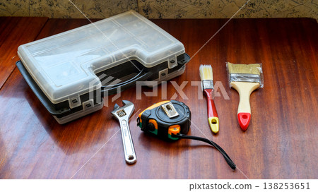closed tool case with a tape measure and brushes on a table closed tool case with a tape measure and brushes on a table 138253651