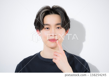 Close-up of a young man looking directly at the camera, showing his concern for his mouth, lips, and skincare. 138254245