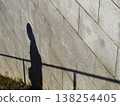 Silhouette of a child walking in the shadow of a fence 138254405