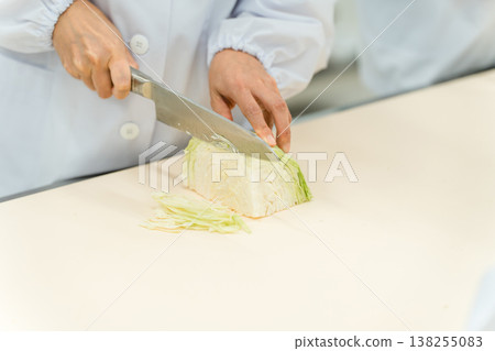 The hands of a staff member cutting cabbage at a food processing plant 138255083