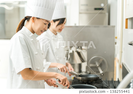 廚房裡使用煎鍋的女廚師。 138255441