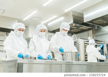 Male and female cooks working in food processing (preparation, simmering) Male and female cooks working in food processing (preparation, simmering) 138255724