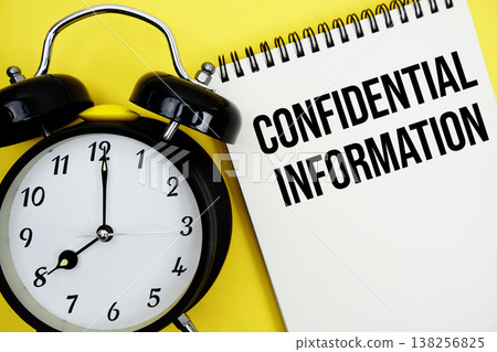 Confidential Information text with alarm clock flat lay on yellow background Confidential Information text with alarm clock flat lay on yellow background 138256825