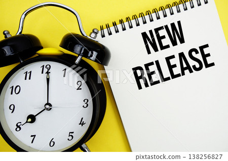 New Release text with alarm clock flat lay on yellow background 138256827