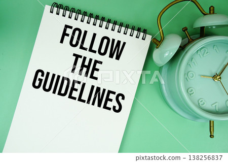 Follow The Guidelines text with alarm clock flat lay on green background 138256837