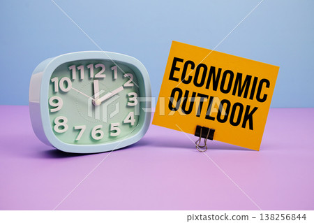 Economic Outlook text and alarm clock on blue and purple background Economic Outlook text and alarm clock on blue and purple background 138256844