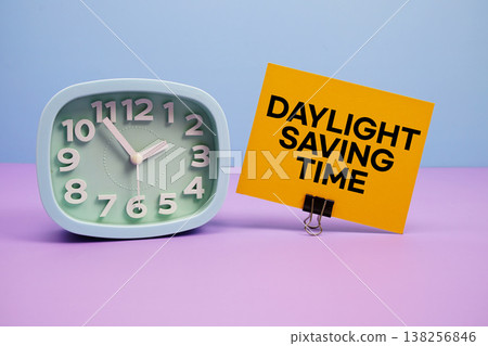 Daylight Saving Time text and alarm clock on blue and purple background Daylight Saving Time text and alarm clock on blue and purple background 138256846