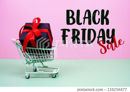 Black Friday Sale text with trolley shopping cart and gift box on pink and green background 138256877