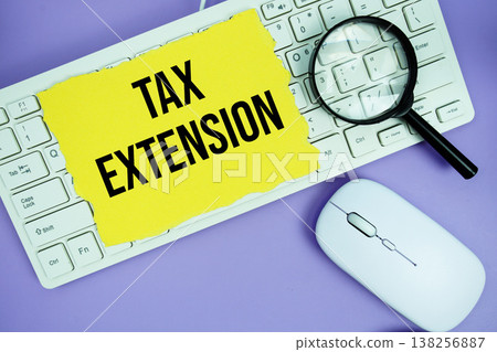 Yellow torn paper with the text "Tax Extension" placed on a white keyboard, and magnifying glass and a computer mouse Yellow torn paper with the text "Tax Extension" placed on a white keyboard, and magnifying glass and a computer mouse 138256887
