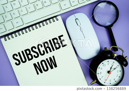 Notepad with the text "Subscribe Now" and white keyboard, wireless mouse, magnifying glass and alarm clock Notepad with the text "Subscribe Now" and white keyboard, wireless mouse, magnifying glass and alarm clock 138256889