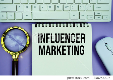 Notepad with the text "Influencer Marketing" with white keyboard, wireless mouse and magnifying glass on purple background Notepad with the text "Influencer Marketing" with white keyboard, wireless mouse and magnifying glass on purple background 138256896