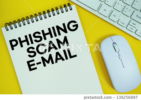 Notepad with the text "E-Mail Phishing Scams" with white keyboard and wireless mouse on yellow background Notepad with the text "E-Mail Phishing Scams" with white keyboard and wireless mouse on yellow background 138256897