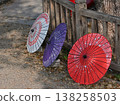 A close-up of three brightly colored Japanese umbrellas lined up on a wooden fence. 138258503
