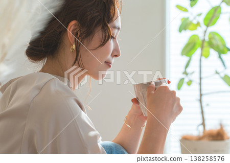 A stylish woman drinking a hot drink in the living room. 138258576