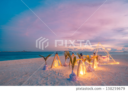 Romantic beach dinner setup with candle lights, table and chairs in heart shape, ocean view sunset, honeymoon or anniversary travel scene Romantic beach dinner setup with candle lights, table and chairs in heart shape, ocean view sunset, honeymoon or anniversary travel scene 138259679