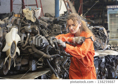 Technician female worker working in garage scrap yard old car part workshop warehouse. 138259887