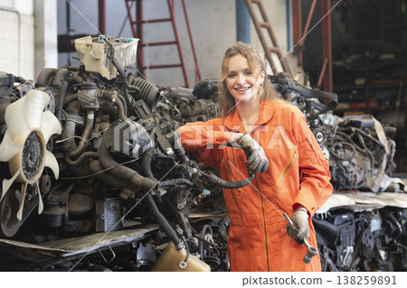 Technician female worker working in garage scrap yard old car part workshop warehouse. 138259891