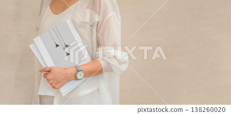 一位衣著時尚的女士手持雜誌或書籍。 一位衣著時尚的女士手持雜誌或書籍。 138260020