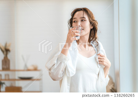 A woman takes a shower and then rehydrates in the living room. 138260265