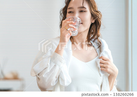 一位女士洗完澡後,在客廳補充水分。 一位女士洗完澡後,在客廳補充水分。 138260266