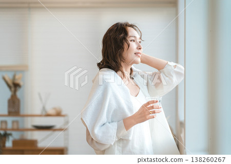 A woman takes a shower and then rehydrates in the living room. A woman takes a shower and then rehydrates in the living room. 138260267