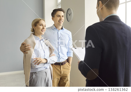 Couple discussing terms with real estate agent during modern apartment viewing 138261362