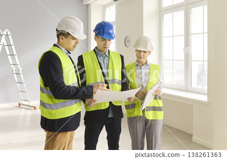 Engineers and contractors review blueprints during interior renovation inspection 138261363