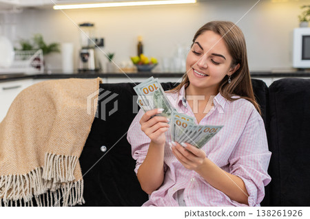 Young woman counts cash dollars smiles about salary savings plans big dream purchase and investments Young woman counts cash dollars smiles about salary savings plans big dream purchase and investments 138261926