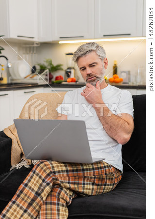 Middle-aged man with laptop on knees writes resume or works freelance remote work focused profile 138262033