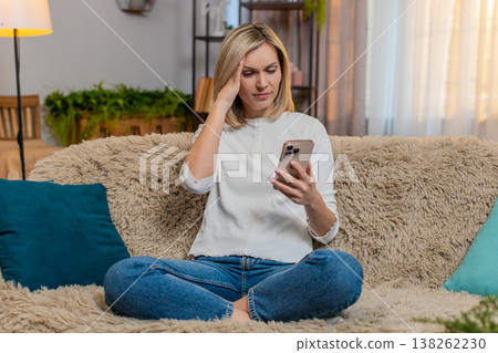 Adult woman disappointed by bad news on smartphone at home sighs with frustration emotional reaction 138262230
