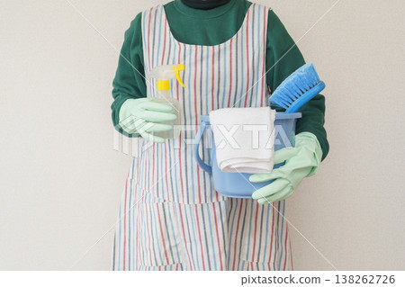 A woman wearing an apron and cleaning tools A woman wearing an apron and cleaning tools 138262726