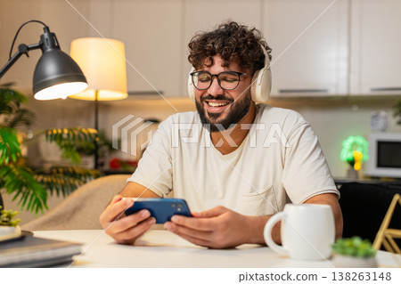 Arabian man in headphones laughs at podcast on smartphone leaves like and writes review in app late Arabian man in headphones laughs at podcast on smartphone leaves like and writes review in app late 138263148