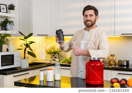 Middle-aged man mixing protein shake in kitchen smiling for fitness diet nutrition workout at home Middle-aged man mixing protein shake in kitchen smiling for fitness diet nutrition workout at home 138263269