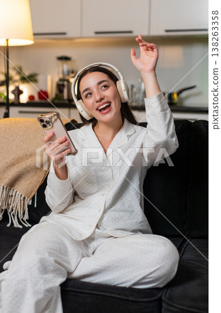 Young woman in wireless headphones enjoys music closes eyes smiles soft head sway calm mood evening 138263358