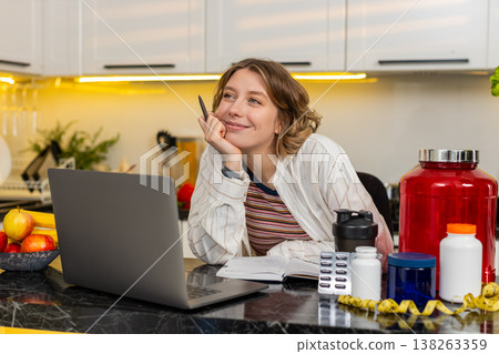 Young woman writing fitness supplement list in notebook for diet plan and healthy workout nutrition 138263359