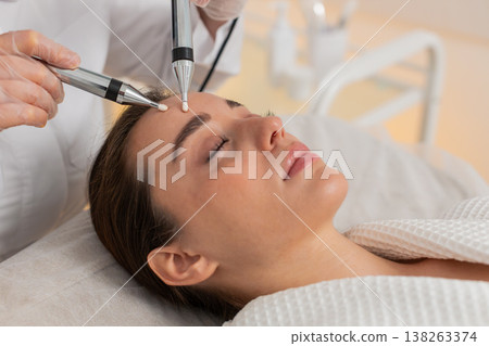 Beautician doctor makes woman micro currents face therapy using electrical impulses in spa salon Beautician doctor makes woman micro currents face therapy using electrical impulses in spa salon 138263374