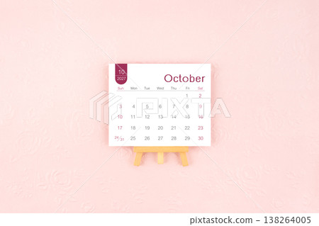 October 2027 calendar page with wooden easel on pink background. 138264005