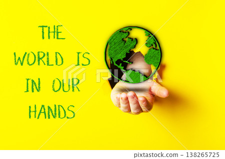Hand holding a green globe symbolizing environmental protection and sustainability, with vibrant yellow background emphasizing the concept of ecology and our responsibility for the planet 138265725