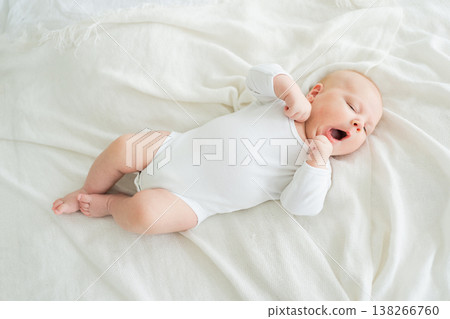 Happy baby. Cute little newborn girl with smiling face lying on bed in bedroom. Infant baby resting playing lying down on white blanket at home. Motherhood happy child childcare concept 138266760