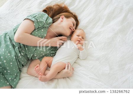 Happy family at home. Mother playing with little toddler child on bed. Mom baby relax playing having fun together. Mother hugs baby with love care. Mom of breast feeding baby rest in living room Happy family at home. Mother playing with little toddler child on bed. Mom baby relax playing having fun together. Mother hugs baby with love care. Mom of breast feeding baby rest in living room 138266762