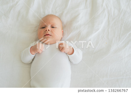 Happy baby. Cute little newborn girl with smiling face lying on bed in bedroom. Infant baby resting playing lying down on white blanket at home. Motherhood happy child childcare concept Happy baby. Cute little newborn girl with smiling face lying on bed in bedroom. Infant baby resting playing lying down on white blanket at home. Motherhood happy child childcare concept 138266767