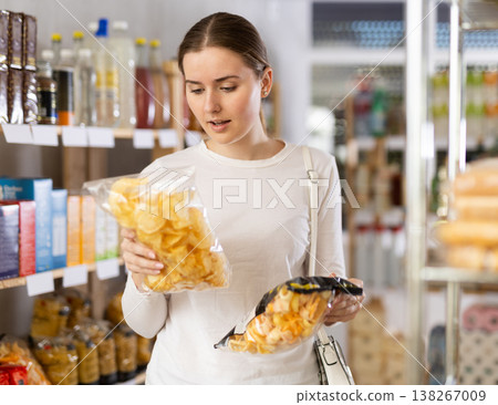Female shopper selects tasty potato chips in supermarket Female shopper selects tasty potato chips in supermarket 138267009