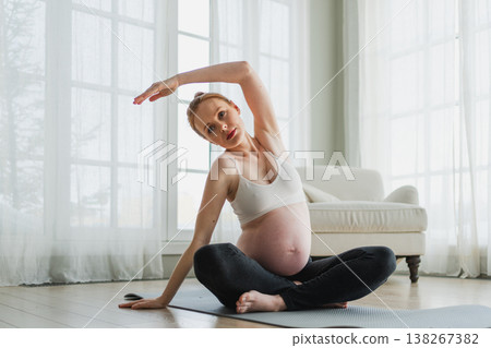 Pregnancy yoga fitness workout training. Pregnant woman practicing yoga at home. Pregnant girl doing sports exercise on yoga mat indoor. Woman with big belly have fitness training practicing asana 138267382