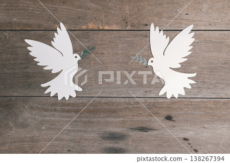 Two white paper-cut doves holding olive branches facing each other on rustic wooden background, flat lay with copy space. Minimal peace, unity and harmony concept for charity posters. peace, harmony Two white paper-cut doves holding olive branches facing each other on rustic wooden background, flat lay with copy space. Minimal peace, unity and harmony concept for charity posters. peace, harmony 138267394