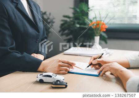 Close-up of car insurance contract signing between client and agent at office desk with model car, key and document, showing vehicle purchase, policy approval, professional service, trust. insurance Close-up of car insurance contract signing between client and agent at office desk with model car, key and document, showing vehicle purchase, policy approval, professional service, trust. insurance 138267507