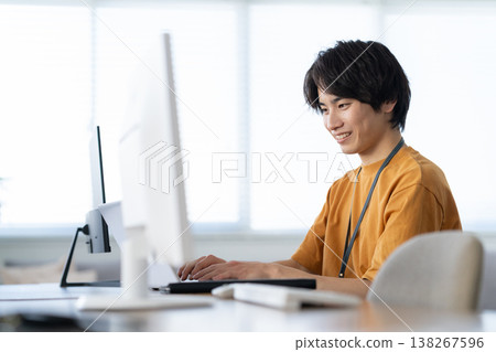 一位年輕的男工程師正在辦公室電腦前工作。 138267596