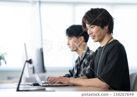 一位年輕的男工程師正在辦公室電腦前工作。 138267649