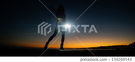 Woman silhouette with strong light flare at sunset Woman silhouette with strong light flare at sunset 138269543