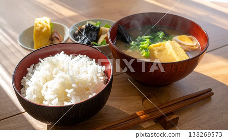 清晨的陽光灑在木桌上，桌上擺放著看起來很美味的小菜、味噌湯和米飯。 138269573