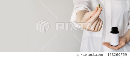 Woman holding green natural capsule and blank label vitamin bottle, banner format Woman holding green natural capsule and blank label vitamin bottle, banner format 138269769